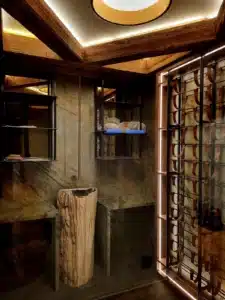 Cave à vin rustique-chic avec lavabo en bois pétrifié, murs en pierre marbrée et casiers à bouteilles en cuir.
